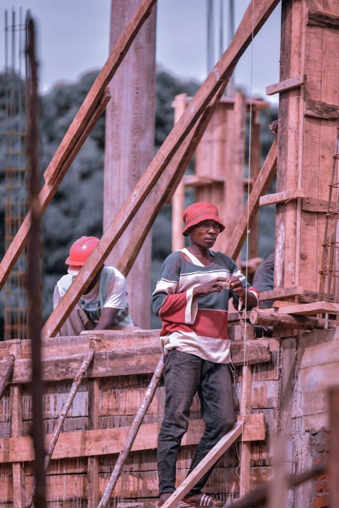 African construction workers on-site handling building materials.